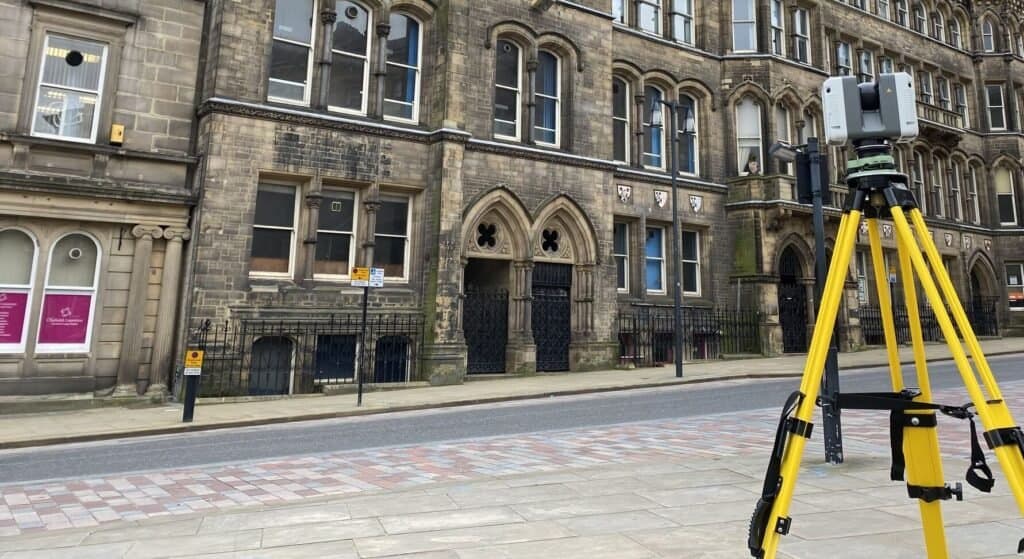 How 3D Laser Scanning Improves Accuracy on Complex Construction Projects 4 - How 3D Laser Scanning Improves Accuracy on Complex Construction Projects Laser scanning device set up on a city street for detailed 3D mapping and surveying, capturing precise measurements of historic building facades.